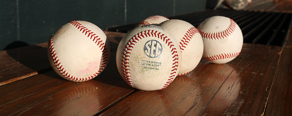 Three baseballs sitting on a wooden bench